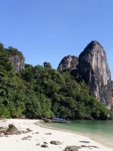 un barco en una playa con rocas en el agua en The Best Bungalow en Ban Bang Chak