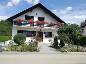 a white house with flowers on the balcony at House Osana in Grabovac