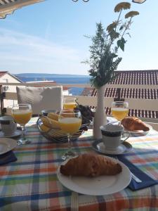 una mesa con un plato de comida y vasos de zumo de naranja en Apartment Gordana, en Trogir