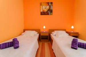 two beds in a room with orange walls and purple pillows at Apartments Amico in Zadar