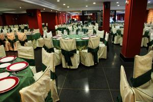 Hostal Los Maños في Albentosa: قاعة احتفالات بطاولات وكراسي خضراء وبيضاء