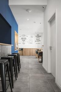 a dining room with black stools and a white wall at Hotel Chesscom in Budapest