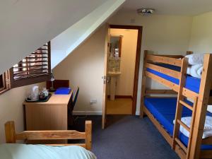 a bedroom with two bunk beds and a desk and a staircase at FSC Slapton Ley Hostel in Kingsbridge