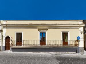 a white building with a balcony on a street at Locanda Sant'Antonio in Aci SantʼAntonio