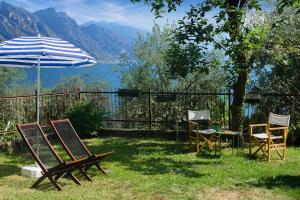 um pátio com cadeiras, um guarda-sol e uma mesa em Discesa a Lago with terrace and garden on lake Iseo em Riva di Solto