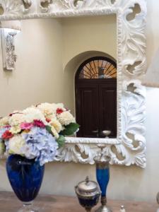 a mirror and two vases with flowers on a table at Locanda Sant'Antonio in Aci SantʼAntonio