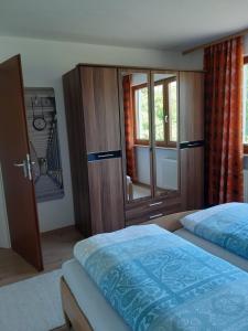 Ferienwohnung Viktoria في لينزكيرش: غرفة نوم بسرير وخزانة خشبية