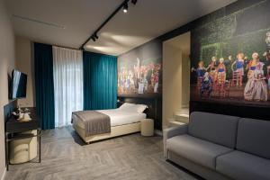 een slaapkamer met een bed, een bank en een schilderij bij Theatrum Rooms and Suite in Verona