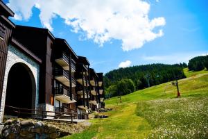 a building on a hill next to a grassy field at Your apartment near the ski lift in Aime-La Plagne