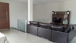 uma sala de estar com um sofá de couro e uma televisão em Recanto Silveira Minas em Capitólio