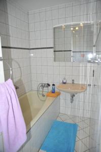 a white tiled bathroom with a sink and a tub at Hotel zur Herzklinik in Bad Oeynhausen