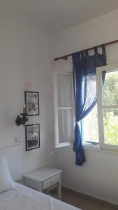 um quarto com uma cama e uma janela com cortinas azuis em Pavlos Rooms em Livadia