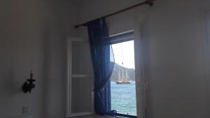 a window with a view of a boat in the water at Pavlos Rooms in Livadia