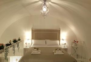 馬泰拉的住宿－SASSO BIANCO，一间卧室配有一张带吊灯的床和2条毛巾