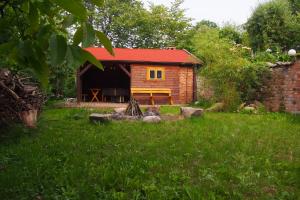 a log cabin with a red roof in a yard at Pokoje u Wojtka Charbrowo in Charbrowo