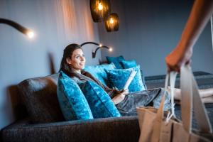 a woman is sitting on a couch with blue pillows at Rofenhof in Naturno