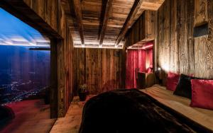 a bedroom with wooden walls and a bed with red pillows at Rofenhof in Naturno
