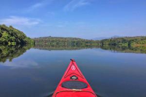 a red kayak on a lake with trees in the background at Amritara Riverside Luxury Tents in Thattakād