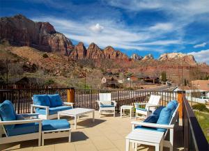 un grupo de sillas y mesas en un patio con montañas en Watchman Villas en Springdale