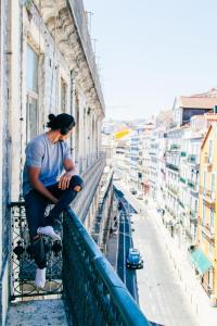 リスボンにあるOutsite Coliving Lisbon - Cais do Sodreの建物のバルコニーに座る男