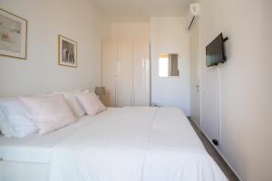 een wit bed met roze kussens in een witte kamer bij Apart SKY Residence with sea view in DELMAR in Budva