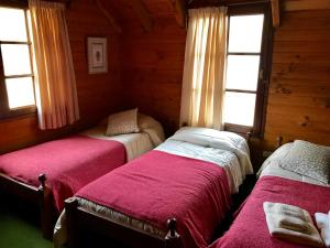 2 camas en una habitación con 2 ventanas en Cabaña frente al lago en San Martín de los Andes
