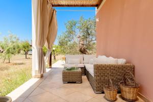 een patio met een bank en rieten stoelen op een veranda bij Villa Nanni in Gallipoli