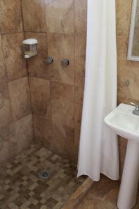 a shower with a white shower curtain next to a sink at Hotel Casablanca Tuxtla in Tuxtla Gutiérrez