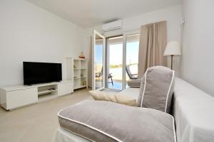 a living room with a tv and a couch and a chair at Apartments Piazza in Nin