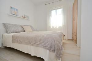 a white bedroom with a bed and a window at Apartments Piazza in Nin
