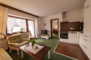 a living room with a couch and a table and a kitchen at Gästehaus Alpenflora in Fischen