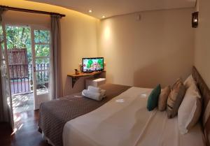 - une chambre avec un grand lit et une télévision murale dans l'établissement Pousada Camburi, à Camburi