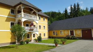 ein gelbes Haus mit einem Balkon und einer Garage in der Unterkunft Ferienwohnungen Gut Seebacher in Klagenfurt am Wörthersee