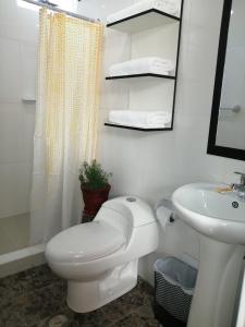 Baño blanco con aseo y lavamanos en Pandora hotel colca, en Chivay