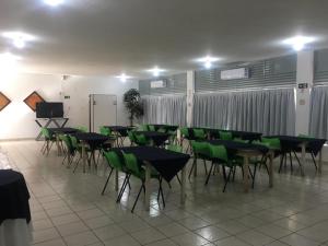 a group of tables and green chairs in a room at Hotel Nautico in Três Marias