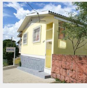 uma casa amarela com uma cerca em frente em Pousada Simone em Cambará