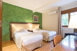 2 camas en una habitación de hotel con paredes verdes en California, en Málaga
