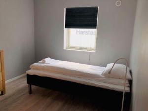 a small bed in a room with a window at Midnattsol pensjonat in Harstad