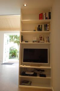 TV de pantalla plana en un estante de libros en Albatros, en Schoorl