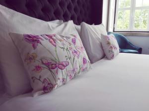 Una cama con almohadas blancas con flores rosas. en Sintra1012 Boutique Guesthouse, en Sintra