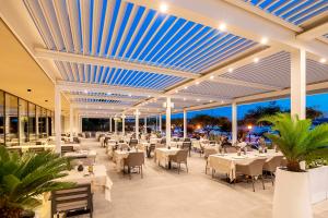 a restaurant with white tables and chairs and blue ceilings at Luxury Hotel Riva in Malinska