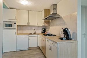 Bakkeveen的住宿－4 persoons appartement - ook te boeken voor 6 personen!，厨房配有白色橱柜和炉灶烤箱。