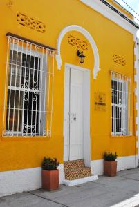 een geel gebouw met een witte deur en ramen bij Hostal Españolete in Santa Marta