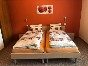 2 Betten in einem Zimmer mit orangefarbenen Wänden in der Unterkunft Ferienhaus Perle in Saas-Grund