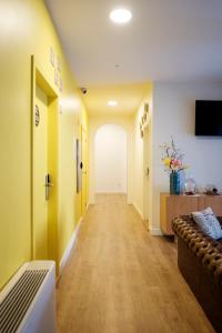 a hallway with yellow walls and a couch in a room at HI!GO in Vila Nova de Famalicão