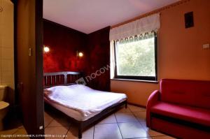 1 dormitorio con cama, ventana y sofá rojo en Agroturystyka Sielana, en Kostrzyca
