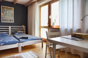 a bedroom with a bed and a desk and a table at Apartament pod Lawortą in Ustrzyki Dolne