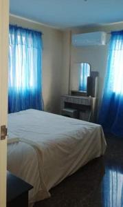 a bedroom with a white bed and blue curtains at Home Away From Home @ the Heart of Batangas City in Batangas City
