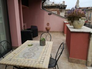 una mesa y sillas en un balcón con un jarrón en Altevolte Rooms, en Catania
