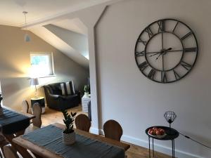 a living room with a table and a clock on the wall at Apartamenty Brzózki in Brzózki +16 photos